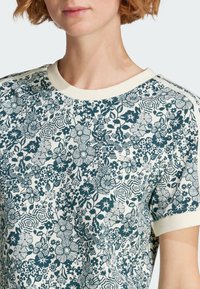 T-shirt a maniche corte con motivo floreale verde e bianco, colletto a coste e tessuto tattile.