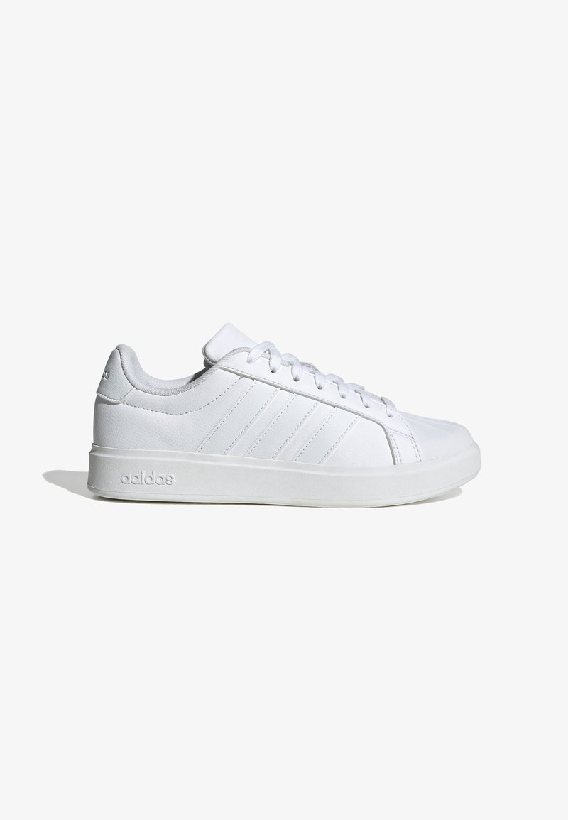 Zapatilla baja blanca de Adidas con cordones en la parte delantera, tres rayas laterales, cuello acolchado y logotipo en relieve en la suela y el talón.