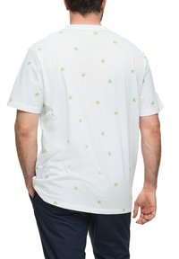 Witte katoenen t-shirt met verspreide kleine groene palmboomprints. Relaxte pasvorm en korte mouwen, met een ronde hals aan de achterkant.
