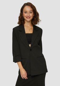 Čierny blazer s voľným strihom, jedn�ým gombíkom na zapínanie, vyhrnutými rukávmi a dvoma prednými vreckami. Hladká textúra, minimalistický dizajn.