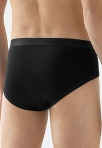 Slip da nuoto neri per uomo caratterizzati da una texture liscia, vita elastica e design aderente. Dettagli minimi per un aspetto pulito e classico.