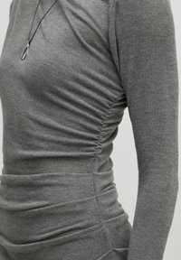Graues Langarmkleid mit Raffung an den Seiten. Weicher Stoff mit glatter Textur. Minimalistisches Design und taillierter Schnitt.