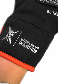 Schwarze Handschuhe mit orangefarbenen Akzenten, versehen mit einem grafischen Logo und dem weißen Text "WORLD CUP WARRIOR", aus strukturiertem, dehnbarem Stoff.