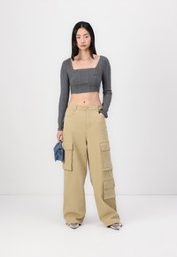 Gray ribbed crop top with a square neckline, paired with beige cargo pants featuring large front pockets. Blue accessory in hand.