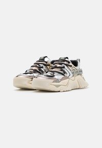 Chunky sneakers in zilver, beige en zwart met gestructureerde materialen, contrasterende panelen, dikke zolen en zwarte veters.