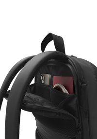 Sac à dos noir avec des bretelles rembourrées, comportant des poches en maille, un téléphone, un passeport rouge et un câble visibles dans le compartiment principal.