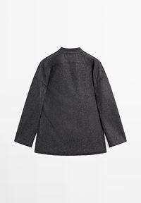 Sort tekstureret jakke med lange ærmer, en lige skæring og en minimalisk krave. Har en subtil glans over hele stoffet.