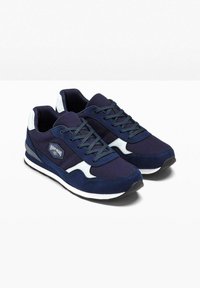 Sneakers blu navy con un mix di tessuto testurizzato e accenti lisci. Presentano un logo bianco, un design con lacci e una suola in gomma nera.