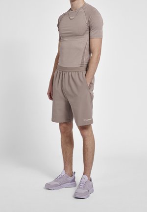 Ropa de deporte para hombres: camiseta ajustada color marrón claro, pantalones cortos sueltos a juego y zapatillas deportivas púrpuras. Textura suave, cinturilla elástica, logo en los pantalones cortos.