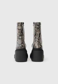 Snake print ankle boots with a high, chunky black platform sole. Upper features a textured finish and a zip closure at the back.