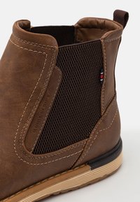 Braune Leder-Stiefelette mit mattem Mesh-Einsatz, elastischen Seiteneinsätzen und kontrastierender heller Sohle. Verfügt über Nähte und Logodetails.