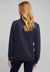 Mörkblå sweatshirt med rund halsringning och långa ärmar, med en avslappnad passform och ribbade cuffs och nederkant. Slät textur överlag.