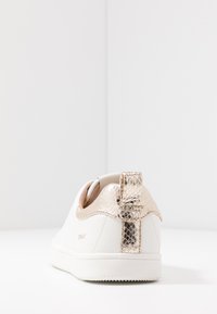 Fehér sneaker, arany textúrájú díszítéssel a saroknál, sima felülettel és kerek formával, fehér talppal. Látható márkaneve: "ONLY".