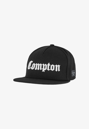 Fekete baseball sapka lapos siluettal, fehér hímzett "Compton" felirattal. Texturált felületű anyagból készült, oldalsó címke látható.