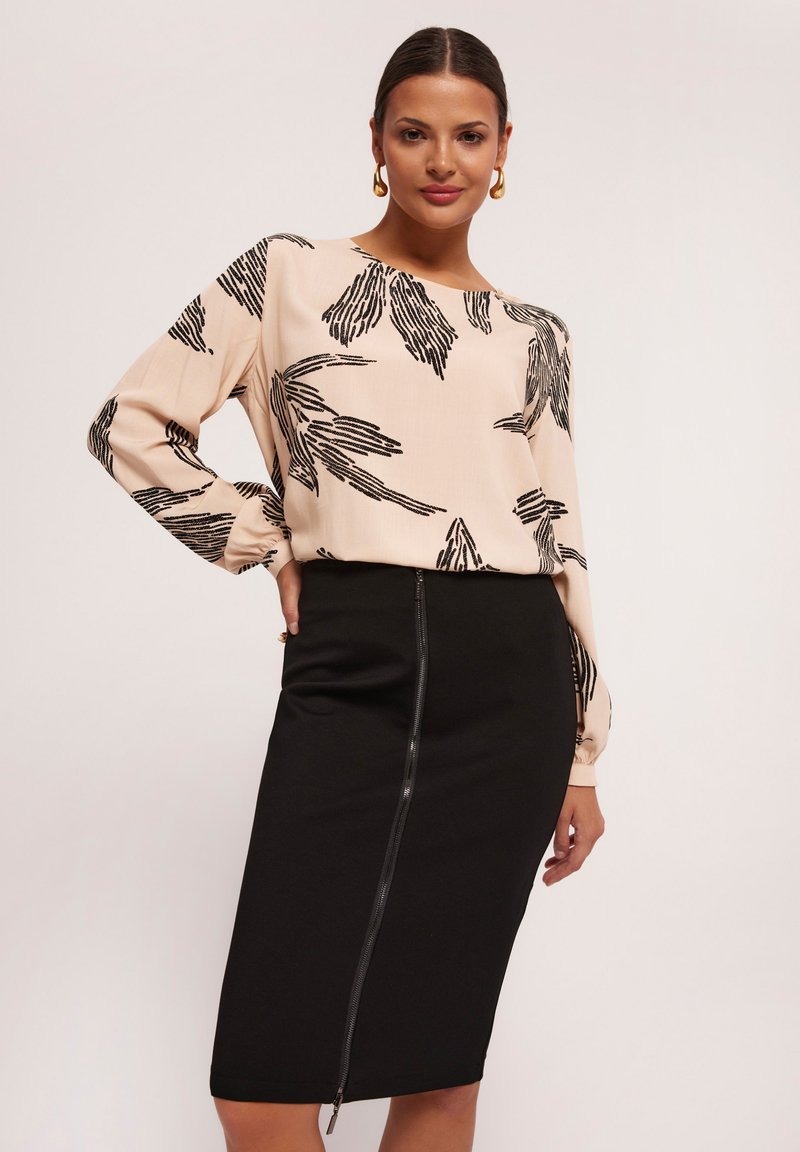 Różowa bluzka z czarnymi wzorami liści, połączona z dopasowaną czarną spódnicą ołówkową z bocznym zamkiem błyskawicznym. Gładka faktura tkaniny i dopasowany krój.