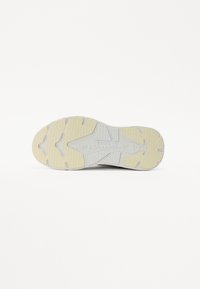 Suola di scarpa da ginnastica con un design prevalentemente bianco, caratterizzata da gomma testurizzata e modelli di battistrada gialli per aderenza e durabilità.