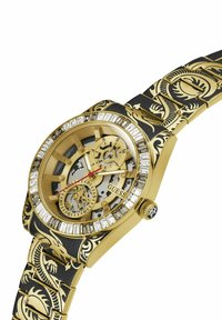 Guldring med et struktureret sort urrem, der har en klar urskive, røde detaljer og en krystalbesat bezel. Indviklet design på remmen.