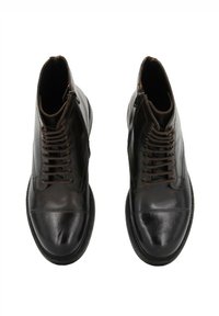 Stivali alla caviglia in pelle marrone con punta rotonda, chiusura con lacci e zip laterale. Texture liscia con dettagli cuciti e suola robusta.