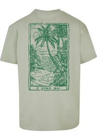 Lys grøn t-shirt i bomuld med et grønt palmetræ grafikon og havscene på ryggen, med teksten "E KOMO MAI" nederst.