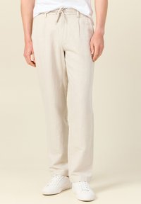 Ljusbeiga linnebyxor med avslappnad passform, som har en elastisk dragsko i midjan, sidofickor och subtila veck för extra detalj.