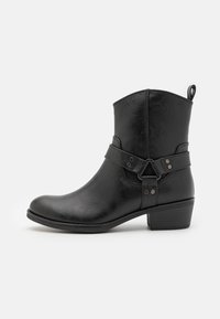 Bottines noires en cuir synthétique texturé, avec une sangle latérale et des accents métalliques, et un talon empilé bas.