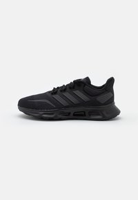 Scarpa sportiva nera con tomaia in mesh, dettagli a motivi, suola imbottita e lacci neri; presenta tre strisce orizzontali sul lato.