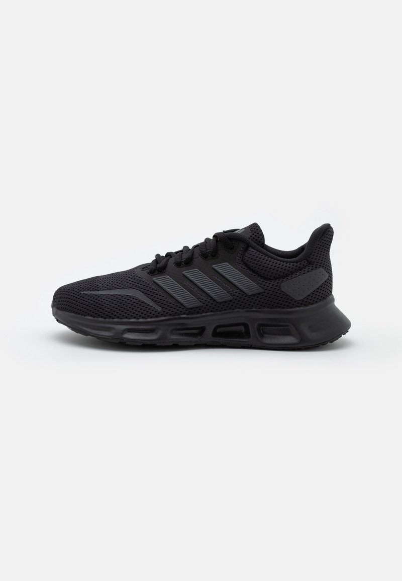 Scarpa sportiva nera con tomaia in mesh, dettagli a motivi, suola imbottita e lacci neri; presenta tre strisce orizzontali sul lato.