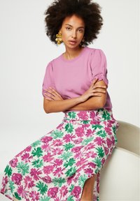 Licht paarse top met korte mouwen gecombineerd met een witte rok met levendige rozen- en groene bloemmotieven; zachte textuur en ontspannen pasvorm.