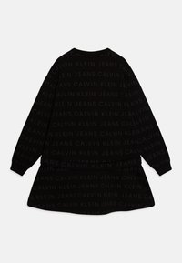 Crna haljina s dugim rukavima i raširenim rubom. Teksturirana tkanina s ponavljajućim, suptilno utisnutim uzorkom "Calvin Klein Jeans" logoa.