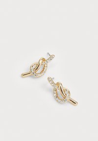 Orecchini a clip placcati oro con design a nodo, accentuati da una barra curva e una fila di piccoli cristalli trasparenti lungo l'anello.