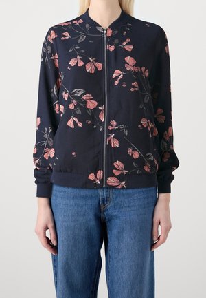 Marineblauwe bloemen bomberjack met roze en grijze bloemenpatronen, ritssluiting aan de voorkant, ribgebreide manchetten en zoom, gecombineerd met blauwe spijkerbroek.