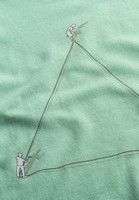 Il tessuto verde menta presenta un design minimalista con due figure; una in piedi su una vetta e l'altra sotto, collegate da una sottile linea.