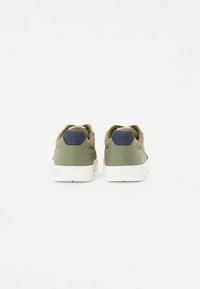 Sneaker verdi con una tomaia in tessuto strutturato, accentuazione del tallone verde scuro a contrasto e suola in gomma bianca. Chiusura con lacci piatti sul davanti.