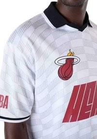 Witte basketbalshirt met zwarte kraag, voorzien van een rood "MIAMI" logo en een rood vlam basketbal logo. Geverfd stof met een subtiel ontwerp.