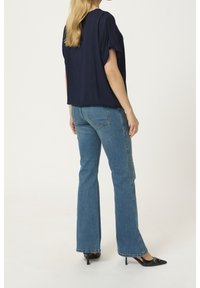 Haut bleu marine à manches courtes avec une coupe décontractée, associé à un jean en denim bleu évasé, avec un design classique à cinq poches et un léger effilochage.