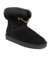 Stivaletto in suede nero con una morbida fodera in pelliccia, dettaglio in catena dorata e suola in gomma testurizzata. Presenta accenti di cucitura a contrasto.