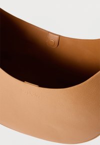 Ταμπά δερμάτινη τσάντα χειρός με υφή στην εξωτερική επιφάνεια και λείο εσωτερικό, διαθέτει μαγνητικό κούμπωμα στο κέντρο της πάνω πλευράς.