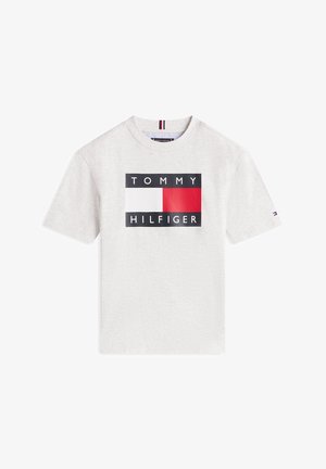 Svetlo siva bombažna majica s kratkimi rokavi, ki ima drzno grafično logotip z črnimi, rdečimi in belimi bloki ter napisom "TOMMY HILFIGER" v črni barvi.