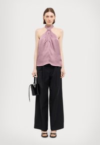 Heled roosa satiinist halter top koos kogutud esiosaga, millele on sobitatud laiad mustad püksid. Must läikiv ämbritasku ja rihmadega sandaalid viimistlevad selle välimuse.