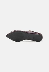 Chaussure en cuir verni bordeaux avec un bout pointu, une boucle décorative et une semelle extérieure en caoutchouc noir texturé. Fini lisse et forme élégante.