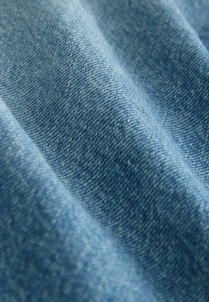 Denimtyg i en medelblå nyans, som visar en subtil struktur med tät väv och mjuk yta, med naturliga variationer i färg.