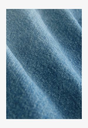 Tessuto in denim di una tonalità blu media, caratterizzato da una sottile texture con una trama fitta e una superficie morbida, con variazioni naturali di colore.