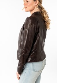 Giacca di pelle marrone con un design fitted, chiusura con zip e texture liscia. Presenta una toppa sulla spalla e dettagli di cucitura snelli.