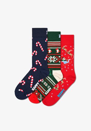 Trzy pary skarpetek: granatowe w cukrowe laski, zielone w świąteczne wzory i czerwone z reniferami, wykonane z miękkiego materiału.