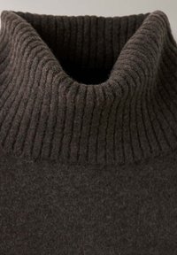 Col roulé côtelé marron foncé sur un pull en maille avec un tissu doux et texturé.