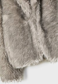 Tissu en fausse fourrure gris clair, doux et à poils longs, avec une texture pelucheuse et des fibres légèrement ondulées, présenté en gros plan sur fond blanc.