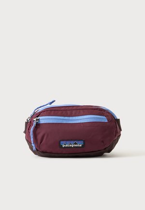 Lille maroon og sort Patagonia talletaske med lyseblå lynlås og logo foran, sat mod en ensartet lys baggrund.