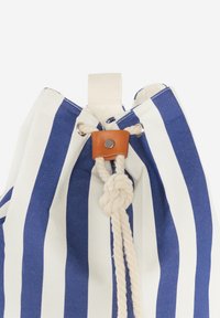 Bolsa de cuerda con rayas en tejido azul marino y blanco, que cuenta con un cierre de cuerda anudada, una pestaña de cuero con herraje de metal y un lazo de tela.