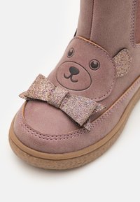 Stivale in ecopelle scamosciata viola con design di faccia d'orso, impreziosito da un fiocco luccicante sul davanti e suola in gomma per una maggiore aderenza.