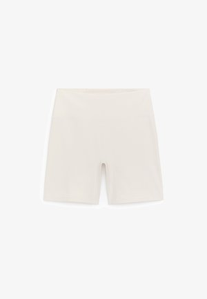 Pantalones cortos de ciclismo de color beige claro hechos de tela elástica, con una cinturilla alta y un diseño liso y ajustado sin ningún herraje visible.